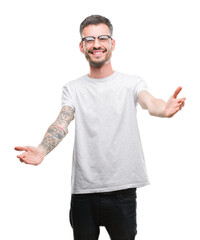 Young tattooed adult man looking at the camera smiling with open arms for hug. Cheerful expression...