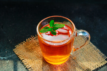 Mint tea in a glass cup on a black background, selective focus