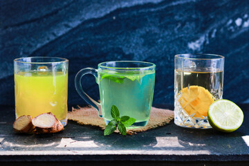Three glasses of lemonade with ginger mint and lemon on a black background