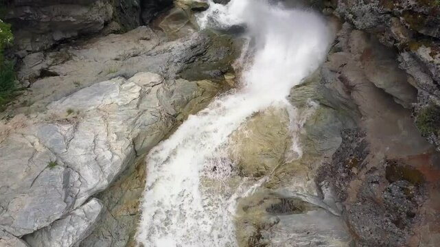 Steep barren rock canyon waterfall aerial flyover looks down into flow