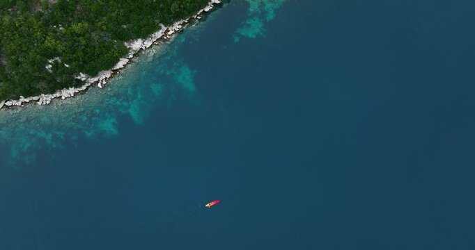 Island landscape, aerial fly kayak sailing pristine sea over green forested island of Mljet