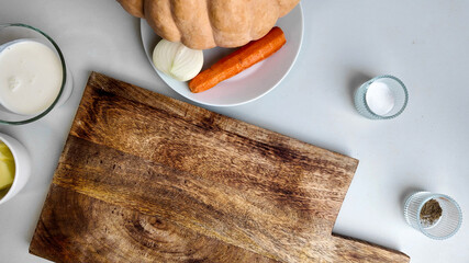 Top view of fresh ingredients for homemade pumpkin soup on a wooden cutting board, ideal for...