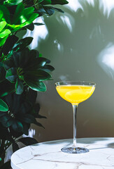 Flying Dutchman, yellow alcoholic cocktail drink with gin, liqueur and lemon juice. Marble table in...