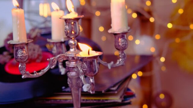 stack of vinyl discs, burning candles in a candlestick, magical objects in a dim room, an atmosphere of magic, the development of imagination, Halloween holiday, cozy musical holiday mood