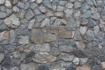 Uneven surface of wall made of gray natural shape fieldstones