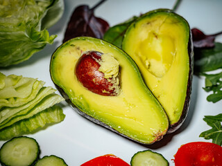 A detailed close-up of a ripe avocado cut in half with the pit in the middle, highlighting its...
