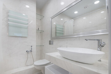 Fototapeta premium Modern bathroom design, decorated in white. Stylish accessories, glass shelves. A large mirror over the sink.