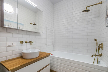 Retro design of the bathroom, decorated with white brick tiles. Brass faucets, showers .and faucets are antique.