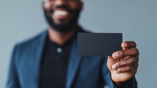 Close-up of biracial man’s hand holding sleek black business card with blank space for personalization, isolated on clean white background, ideal for professional branding, networking, or corporate id