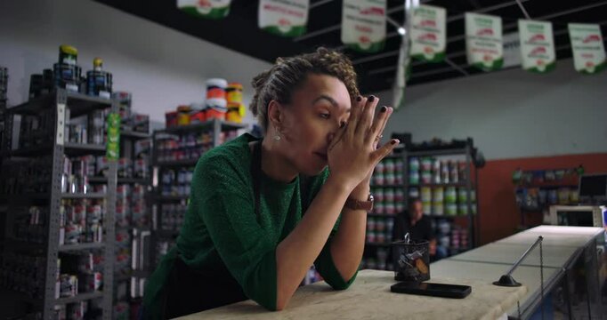 Overwhelmed female shop owner leaning on counter in distress, struggling with financial challenges, emotional moment in retail store, small business crisis
