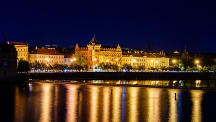A breathtaking long exposure photo of Prague, Czech Republic at night, showcasing the Vltava River, Prague Castle, and National Theatre, all under a clear, starry sky.