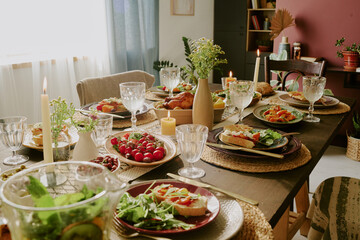 High angle shot of table with served plates with gourmet salad, snack and jars of lemonade