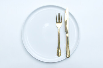 Modern tableware setup with a fork, spoon, and ceramic plate to emphasize dining refinement.
