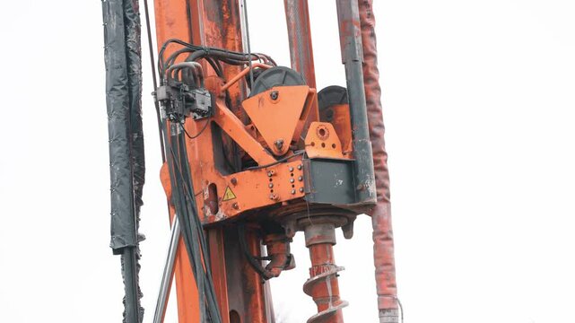 Heavy machinery pile auger rig drills into ground at construction site in urban environment