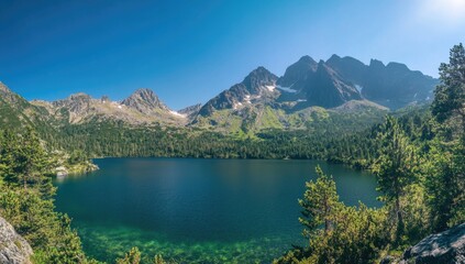 Naklejka premium Majestic mountains rise sharply above a crystal-clear lake, surrounded by vibrant greenery and bright blue sky. Sunlight dances on the water's surface, inviting peaceful reflection