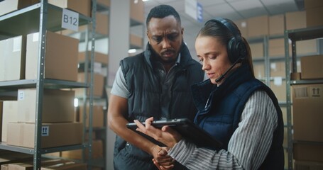 Female Logistics Coordinator Wearing Headset Uses Tablet Computer in Warehouse Facility, African...