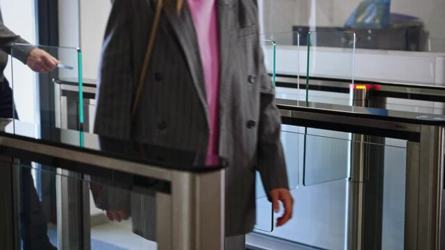 Passing through a turnstile into an office building. Office workers enter and exit through a modern turnstile, using a key card to enter.