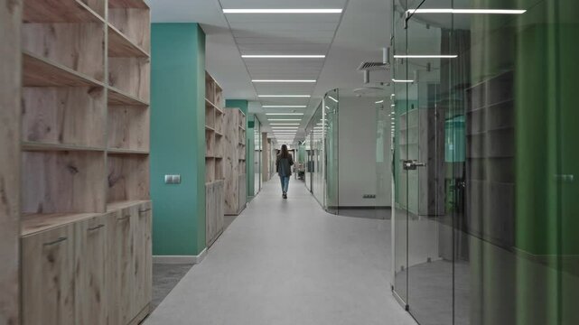 The camera moves around a modern office space, on the left and right are meeting rooms, offices and cabinets. Business commercial real estate.