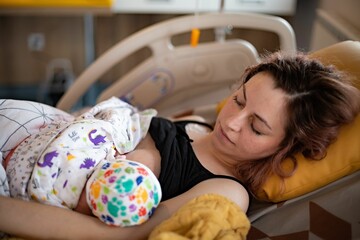 Young mother in her 20s peacefully breastfeeding her newborn in a hospital bed