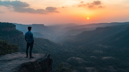 Obraz premium Man Standing at Cliff Edge Watching Scenic Landscape at Sunset