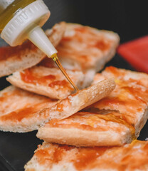 Verter aceite de oliva sobre rebanadas de pan tostado. Enfoque selectivo.