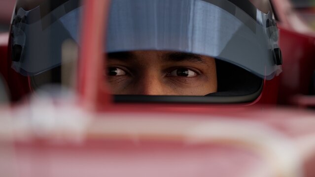 Close-up of a focused pilot driver in a red racing car, preparing for a race