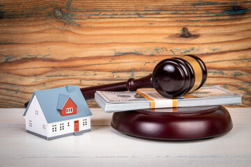 Inheritance dispute. Judge's gavel, money and miniature house on a wooden texture backgroun
