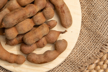 Rustic wooden board featuring freshly picked tamarind pods for an authentic natural look.