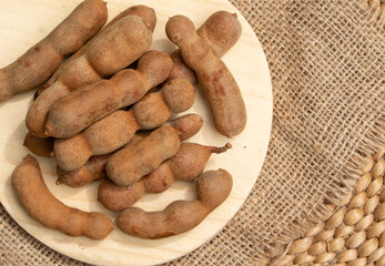 Organic tamarind fruits resting on a wooden surface, emphasizing their earthy tones.