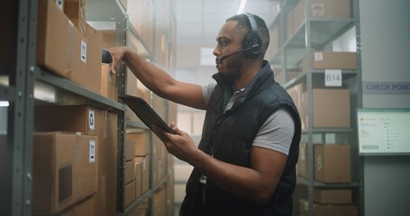 African American Warehouse Associate in Headset Scans Cardboard Boxes with Online Goods, Checks...