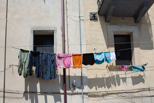 Colorful clothes drying on a line attached to a rustic building facade in Naples, Italy, representing urban poverty