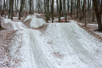 Unpaved ramps and paths for performing stunts on a bicycle or motorcycle in a snowy park.