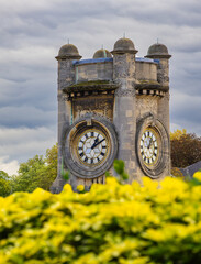 A close-up view of a historic clock tower of Horniman museum, lush greenery and vibrant yellow...