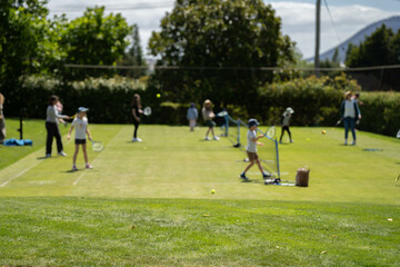 children playing tennis on grass, kids playing lawn tennis in australia as a family in summer
