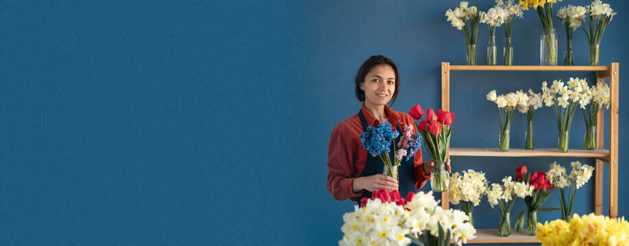 Floristry concept. florist wear apron holding red tulips in her flower shop.