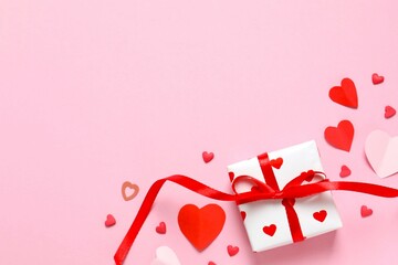 Beautiful gift box with red hearts on color background