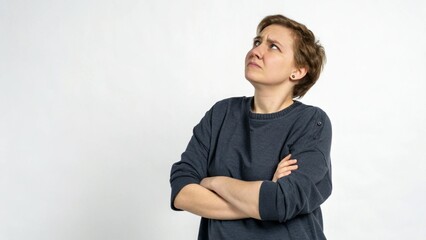 Person with crossed arms shows skepticism while looking upwards in a well lit indoor space during daytime