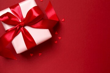 Beautiful gift box with red hearts on color background