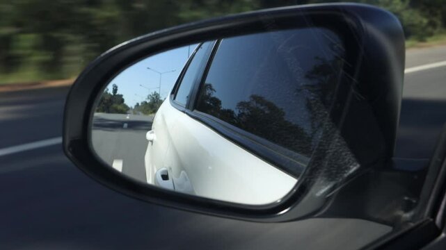 A Looking in the rear view mirror while driving on the road.