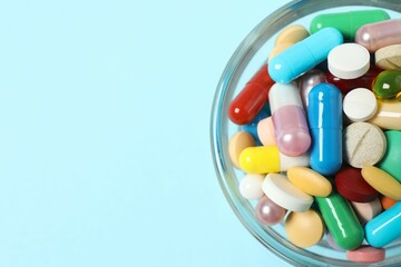 Various pills in a bowl on color background
