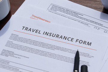 Obraz premium A travel insurance form prepared with essentials: pen and coffee, creating a practical office desk setup.
