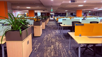 office space with work desks and chairs alley lined with half cupboards and plant pots on top of them