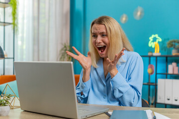 Displeased sad businesswoman using laptop notebook typing browsing working loses becoming surprised...