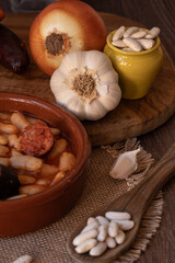 Traditional Asturian fabada ingredients and cooked dish on rustic wooden table