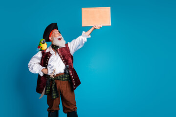 Photo portrait of senior funny pirate grandpa hold look picture frame wear masquerade party costume isolated blue color background
