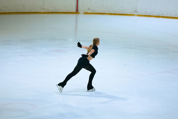 Figure skating girl training on ice arena.