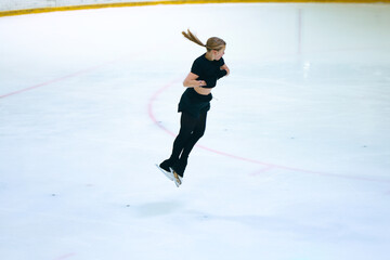 Figure skating girl training on ice arena.