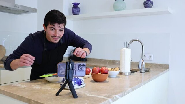 Young man setting up his cell phone to start recording a tutorial of a dessert recipe at home