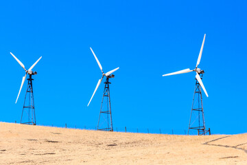 Three wind turbines are standing on a hill in a field