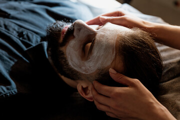 Facial, skin care, relaxation with a bearded man in the spa, beauty, mud, and hydrating mask....